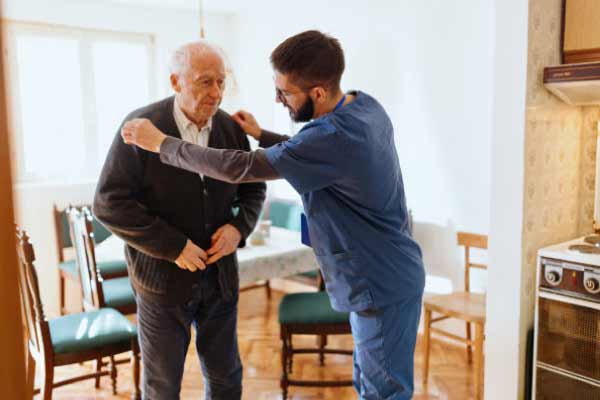 Agile In-Home Care caregiver helping an elderly man with his sweater